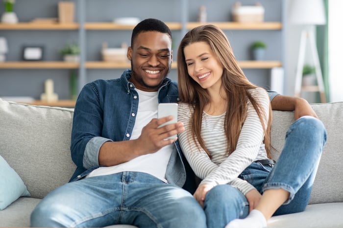 Couple on couch looking at phone together learning about a company through a marketing message